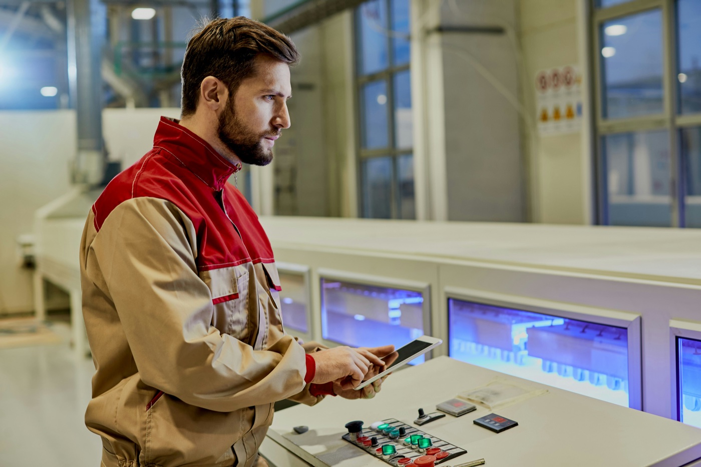 Un homme consulte son téléphone dans un environnement industriel.